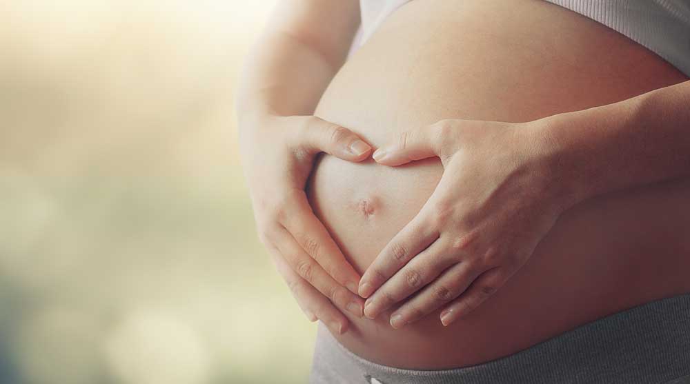 Pregnant woman with heart-shaped hands